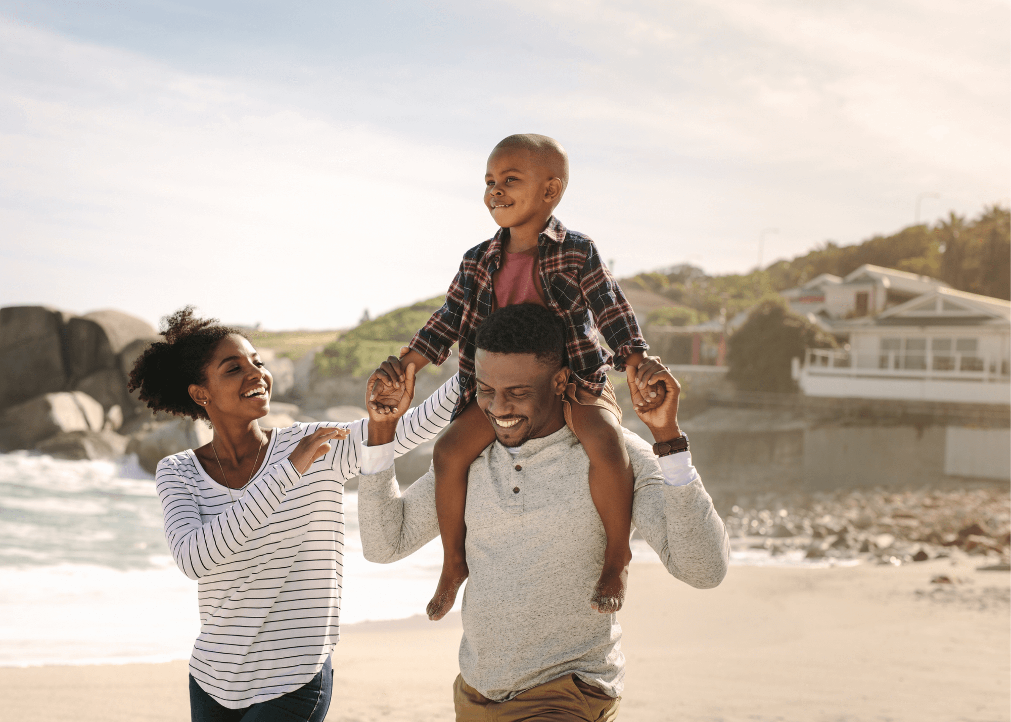 Family smiling on the beach; child sitting on top of fathers shoulders - Alles Law